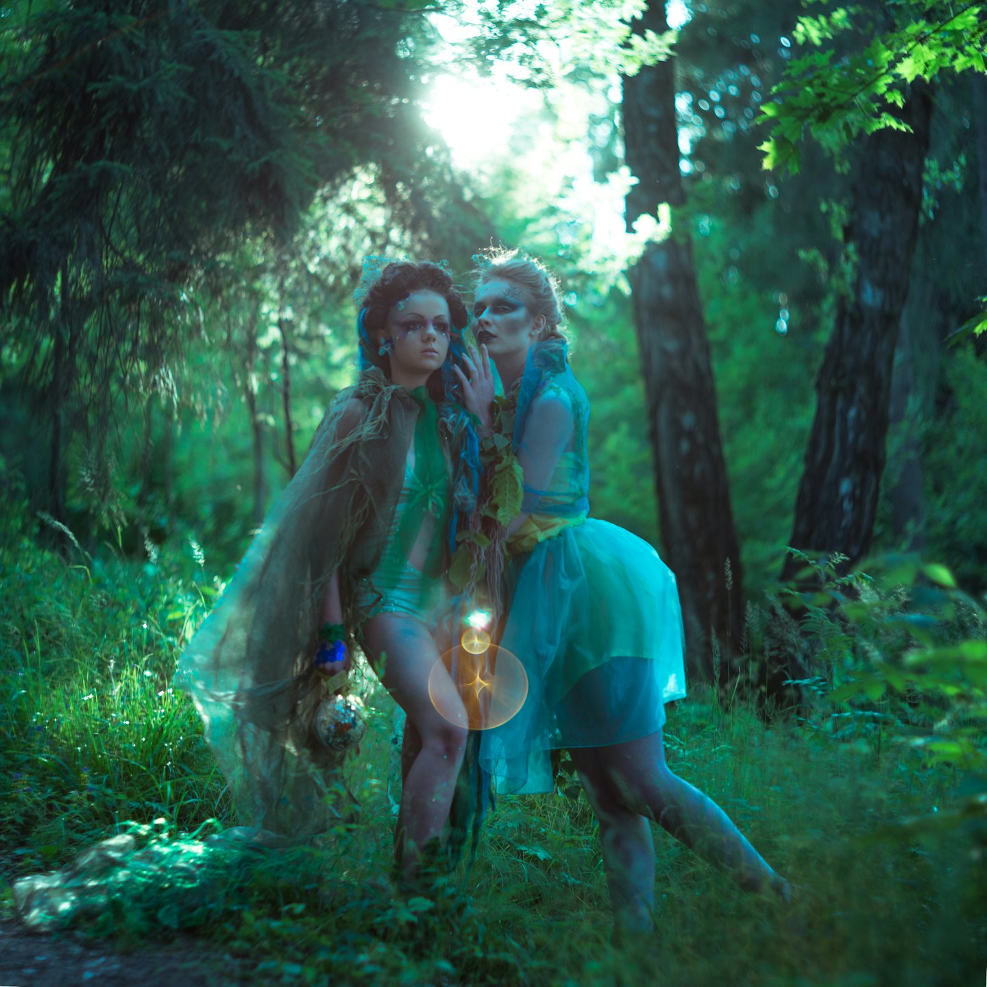 Two people in fantasy costumes stand together in a forest.