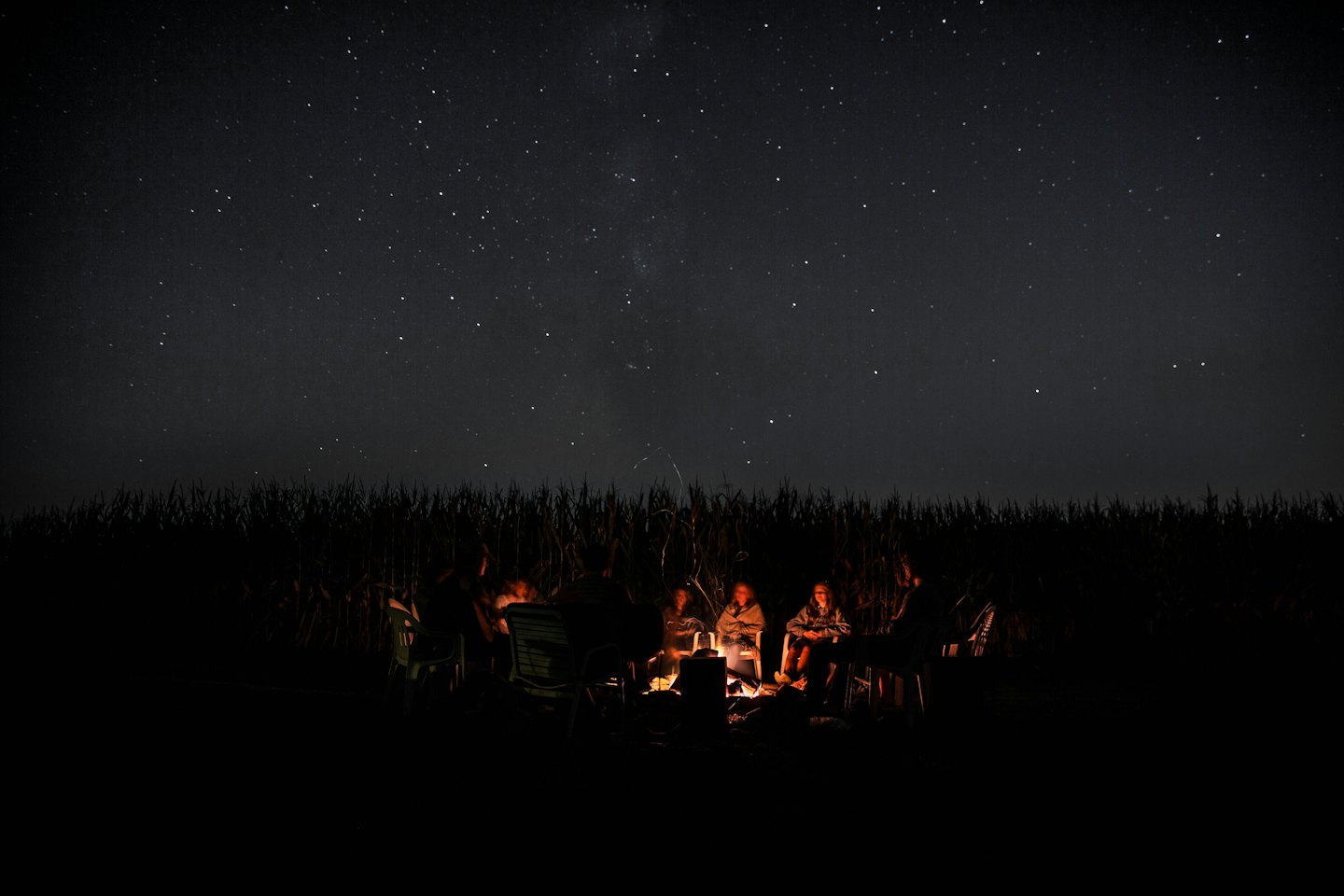 People gathered around a campfire in a field at night.