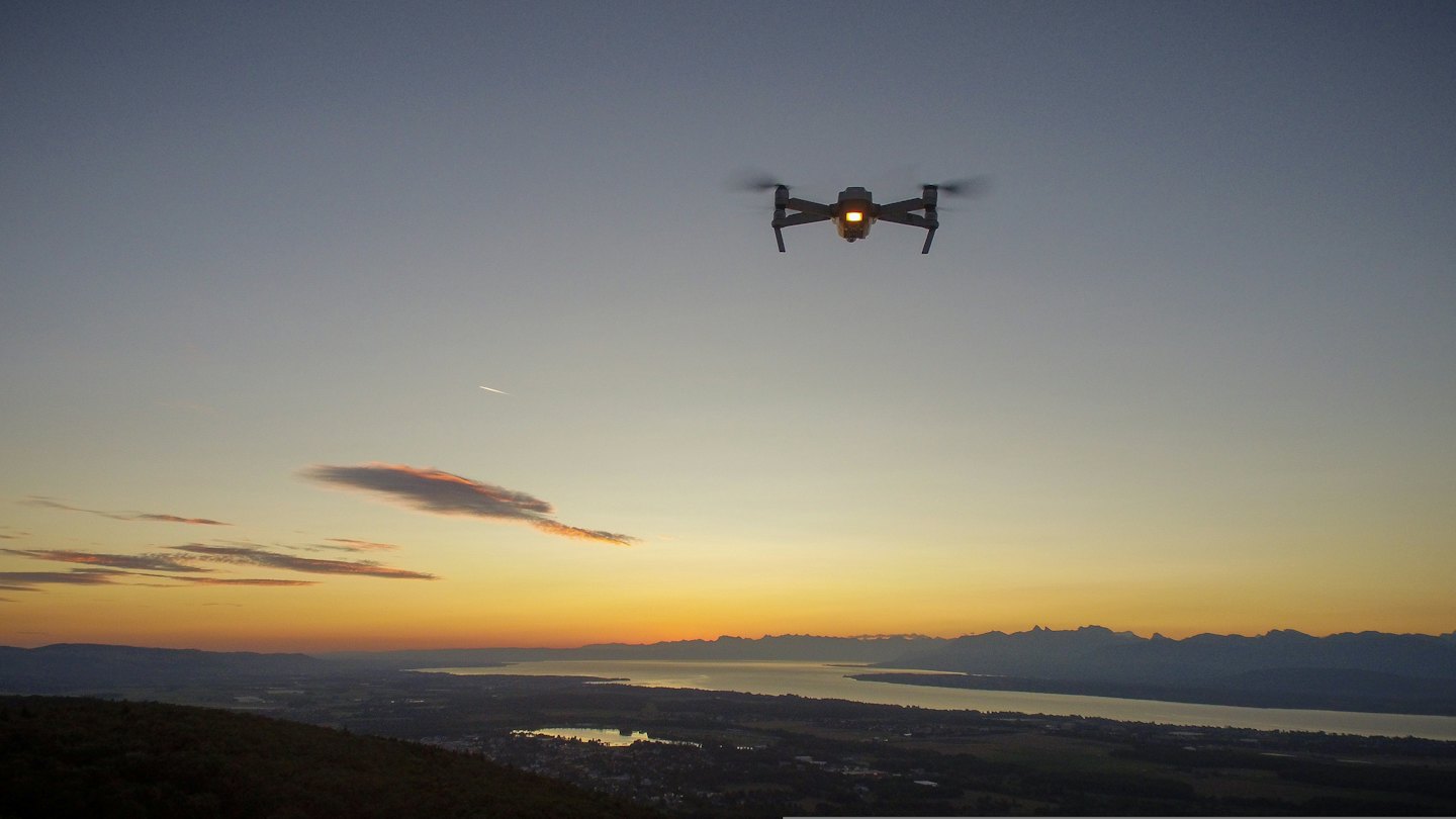Drone flying over a lake at sunset with mountains.