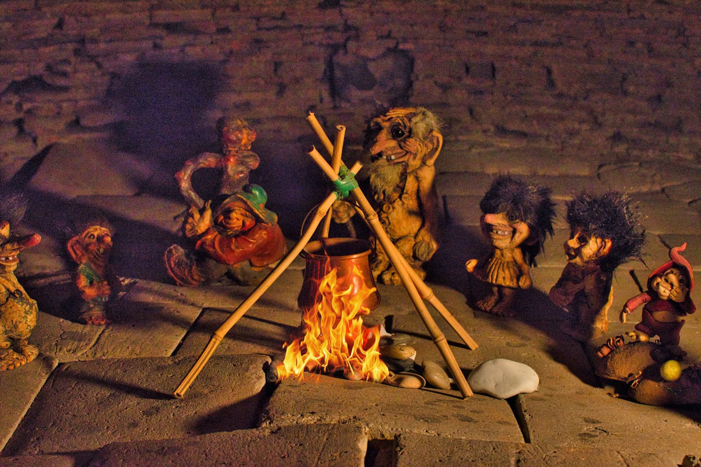 Whimsical gnome figurines sit around a small glowing campfire.